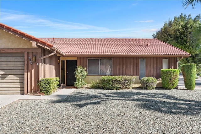 ranch-style home featuring stucco siding, a garage, and a tiled roof