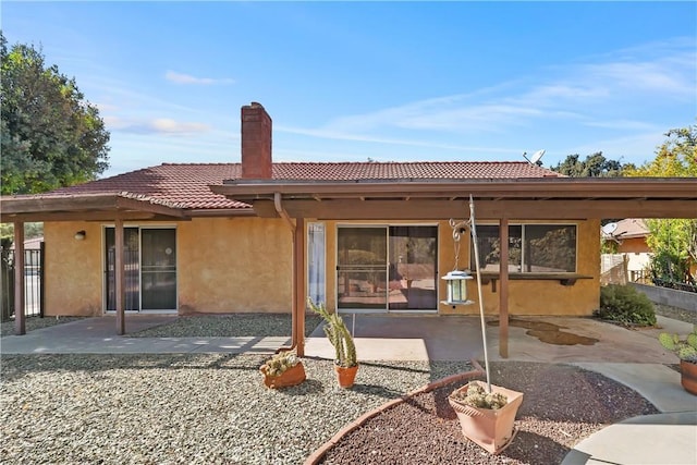 rear view of property with a tiled roof, stucco siding, and a patio area
