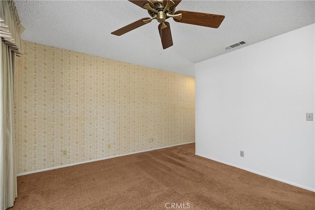 empty room featuring wallpapered walls, visible vents, carpet floors, and a textured ceiling