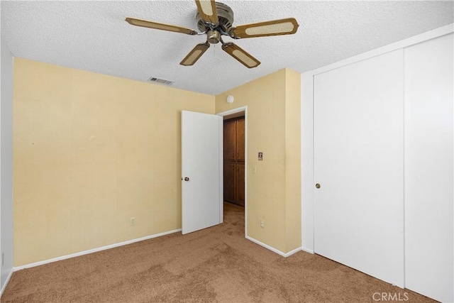 unfurnished bedroom with ceiling fan, light colored carpet, a textured ceiling, and a closet