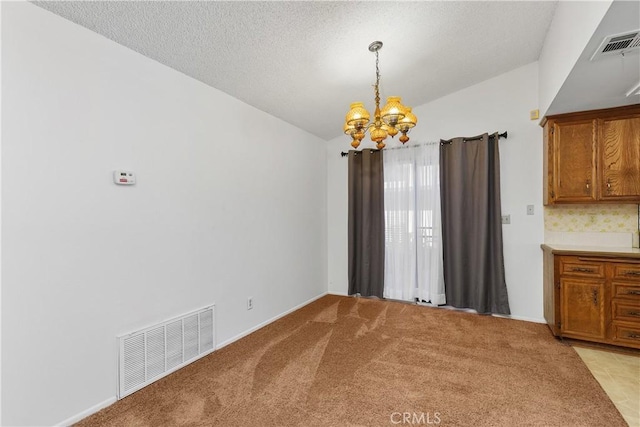 unfurnished dining area featuring light carpet, an inviting chandelier, and a textured ceiling