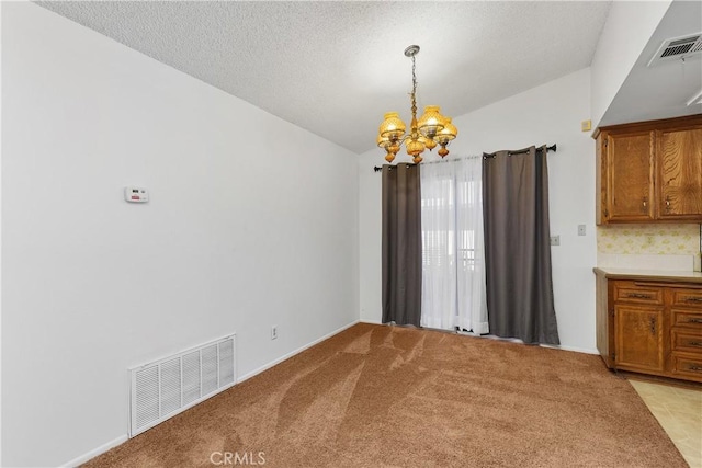 unfurnished dining area with light colored carpet, visible vents, a notable chandelier, and vaulted ceiling