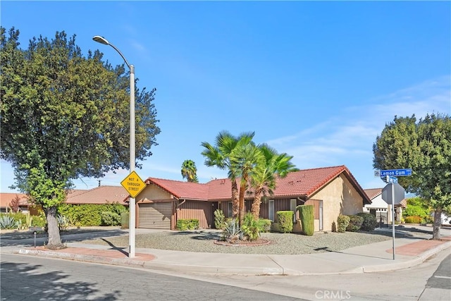 view of front of property with stucco siding, driveway, a garage, and a tiled roof