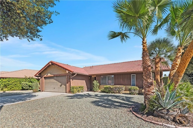 ranch-style house featuring a tiled roof, driveway, and a garage