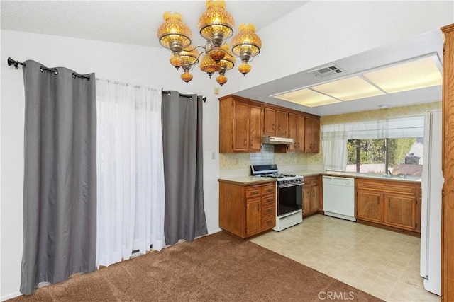 kitchen with decorative backsplash, light carpet, white appliances, an inviting chandelier, and hanging light fixtures