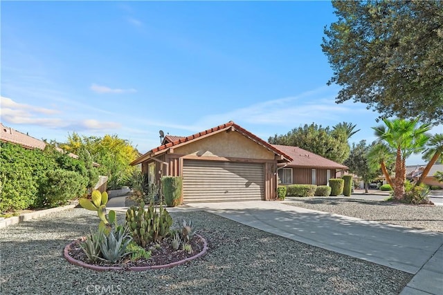view of front of house featuring stucco siding, a tile roof, a garage, and concrete driveway