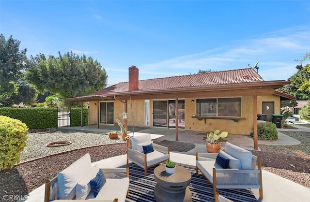 back of house featuring an outdoor living space, a tiled roof, a patio, and a chimney