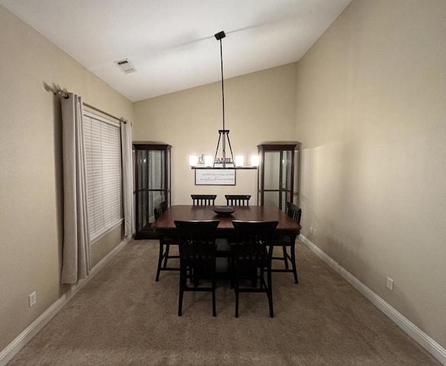 dining room with carpet flooring, lofted ceiling, and a notable chandelier