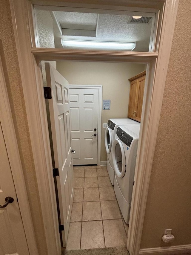 laundry area with washer and dryer, cabinets, and light tile patterned floors