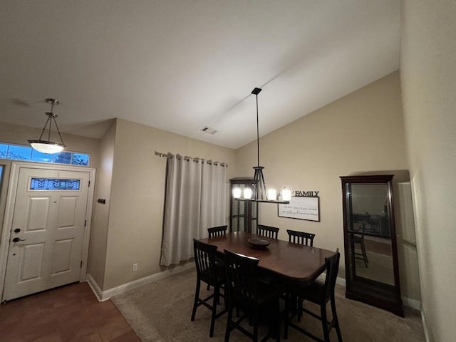 dining space featuring dark carpet, lofted ceiling, and a notable chandelier