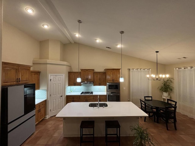 kitchen featuring backsplash, stainless steel appliances, a kitchen island with sink, sink, and lofted ceiling