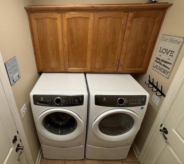 laundry room with cabinets, light tile patterned floors, and washer and dryer