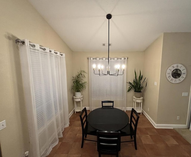 tiled dining space featuring a chandelier and vaulted ceiling