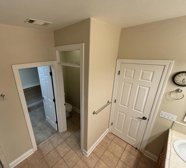 bathroom featuring tile patterned flooring, a textured ceiling, vanity, and toilet