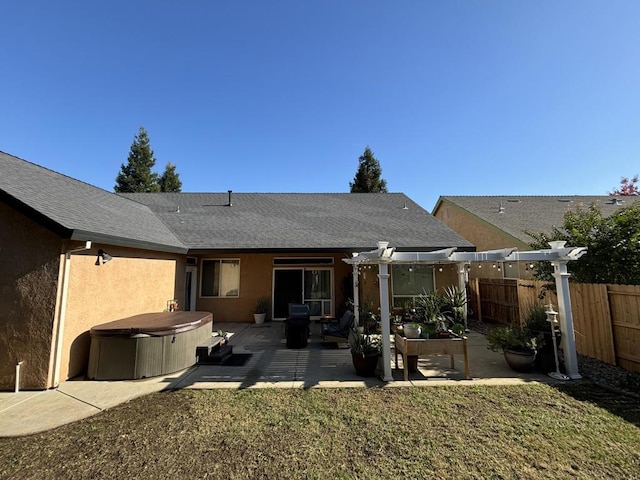 rear view of house with a pergola, a patio, a yard, and a hot tub