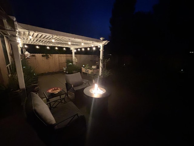 patio at night featuring a pergola and an outdoor fire pit