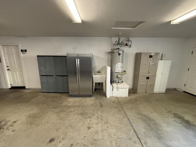 garage with stainless steel refrigerator, sink, and gas water heater