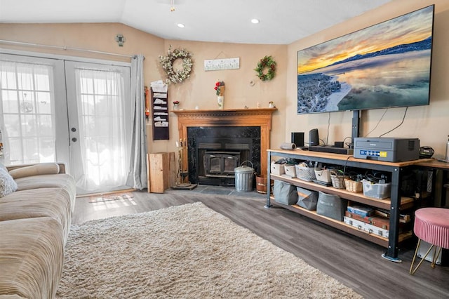 living room featuring wood-type flooring, vaulted ceiling, a wood stove, and french doors