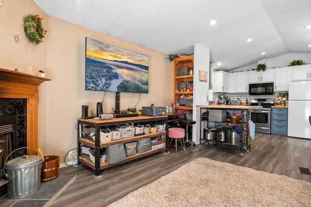 kitchen featuring dark hardwood / wood-style flooring, stainless steel range with electric stovetop, white fridge, white cabinetry, and lofted ceiling