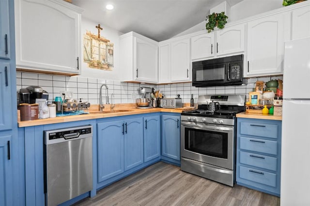 kitchen featuring white cabinets, backsplash, stainless steel appliances, and light hardwood / wood-style flooring