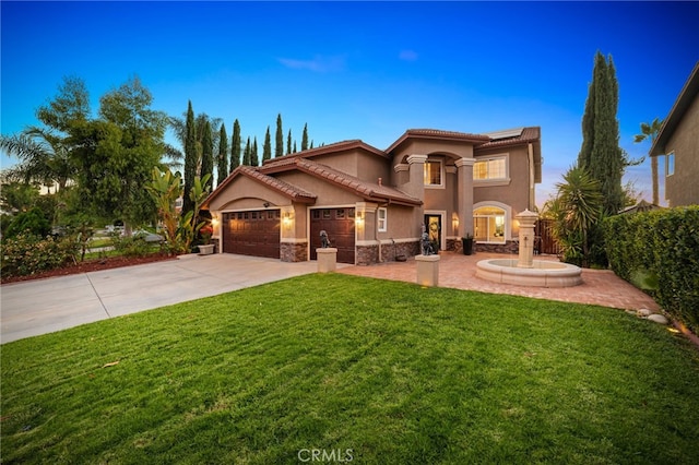 mediterranean / spanish home featuring concrete driveway, stone siding, a tile roof, an attached garage, and a front yard