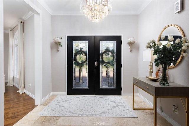 foyer with an inviting chandelier, crown molding, light hardwood / wood-style floors, and french doors