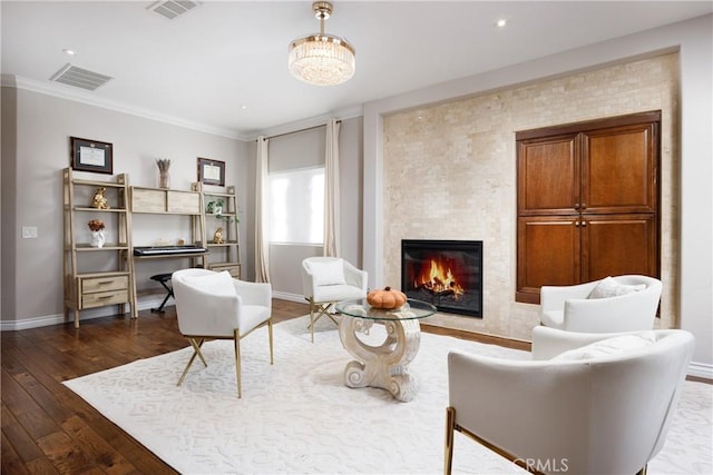 living area with dark wood-type flooring, ornamental molding, and a fireplace