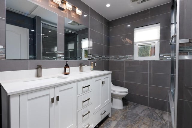 bathroom with toilet, tile walls, a shower with shower door, and vanity