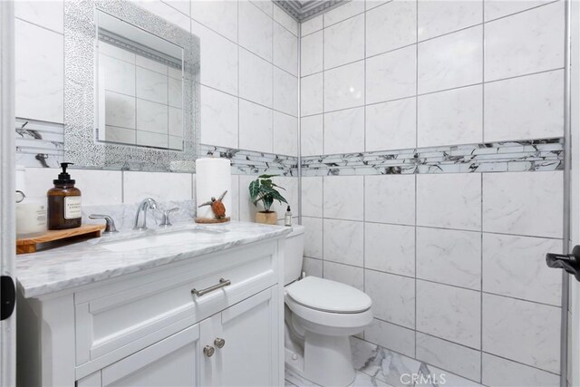 bathroom with toilet, tile walls, and vanity