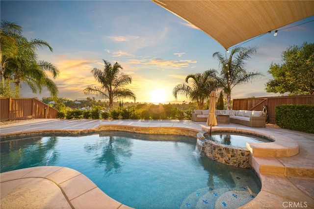 pool at dusk featuring an outdoor hangout area and an in ground hot tub