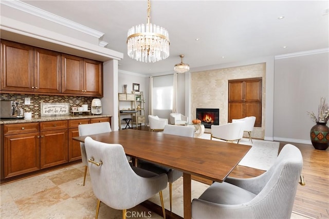 dining room featuring ornamental molding, a chandelier, and a fireplace