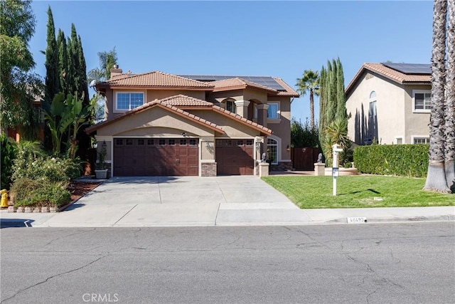 mediterranean / spanish home with driveway, a tile roof, roof mounted solar panels, a front lawn, and stucco siding