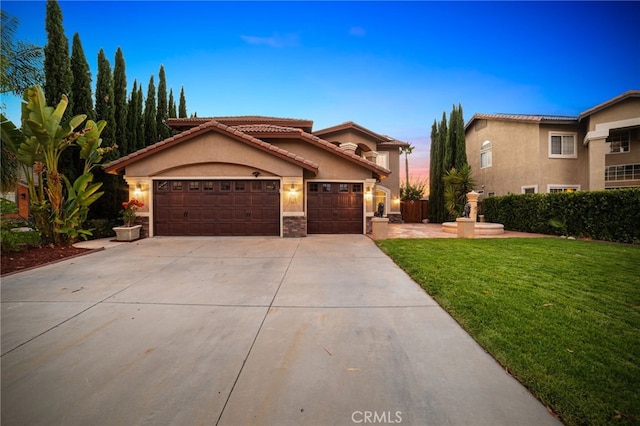 mediterranean / spanish home featuring a yard and a garage