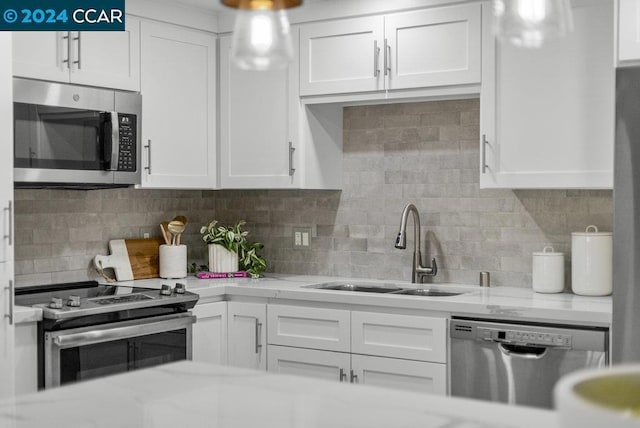 kitchen featuring decorative backsplash, appliances with stainless steel finishes, white cabinetry, and sink