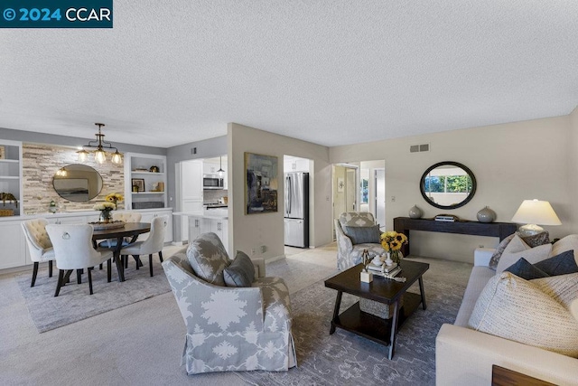 living room with built in features, light colored carpet, and a textured ceiling