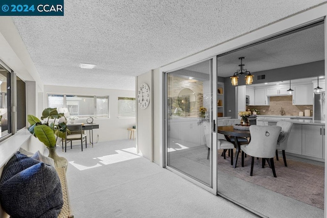 interior space with a textured ceiling, light colored carpet, an inviting chandelier, and sink