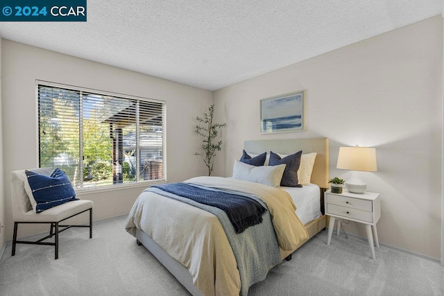 bedroom featuring light carpet and a textured ceiling