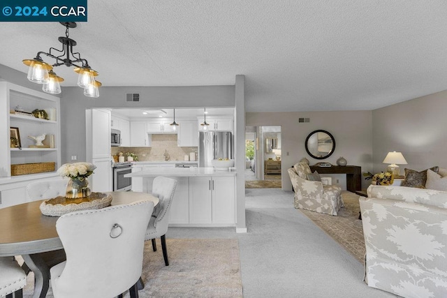 interior space with pendant lighting, white cabinets, light colored carpet, and stainless steel appliances