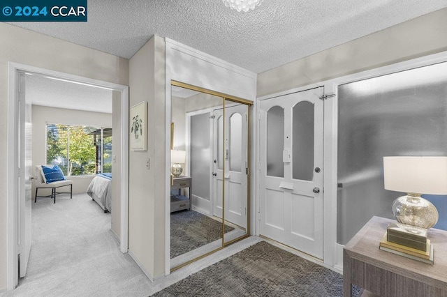 carpeted entryway with a textured ceiling