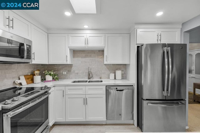 kitchen with backsplash, stainless steel appliances, sink, white cabinets, and light hardwood / wood-style floors