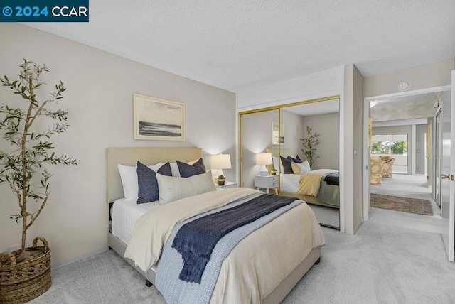 carpeted bedroom with a textured ceiling and a closet