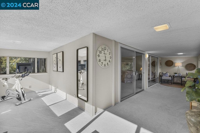 hall with carpet floors and a textured ceiling