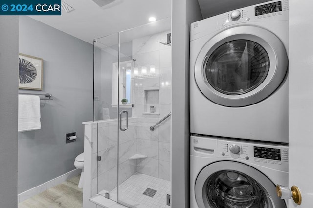 washroom featuring light hardwood / wood-style flooring and stacked washer / drying machine