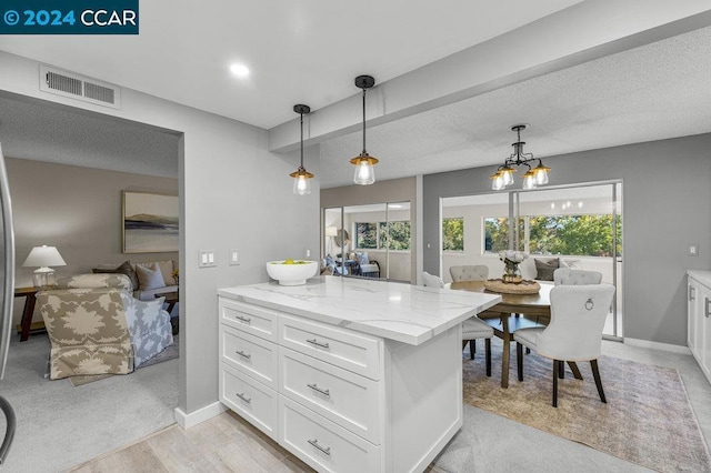 kitchen with light carpet, white cabinetry, hanging light fixtures, and light stone counters