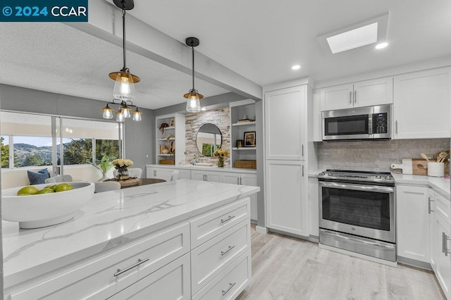 kitchen featuring white cabinets, hanging light fixtures, light hardwood / wood-style flooring, appliances with stainless steel finishes, and light stone counters