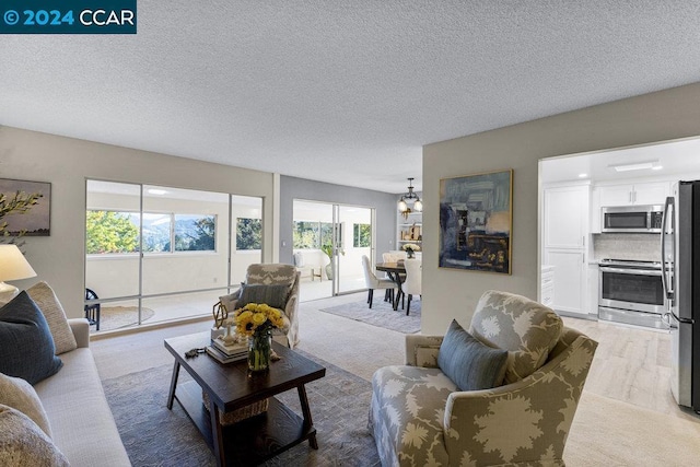 living room with a textured ceiling, light colored carpet, and a notable chandelier