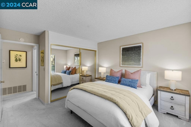 bedroom with a textured ceiling, light carpet, and a closet