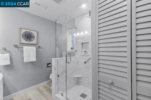 bathroom featuring wood-type flooring, an enclosed shower, and toilet