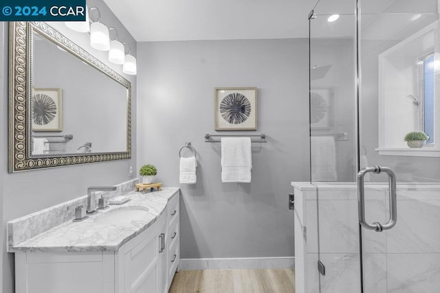 bathroom featuring hardwood / wood-style floors, vanity, and a shower with shower door