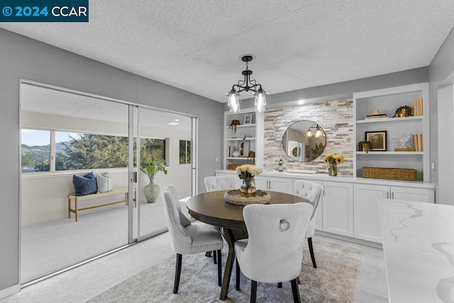 dining room featuring light carpet, built in shelves, and a textured ceiling